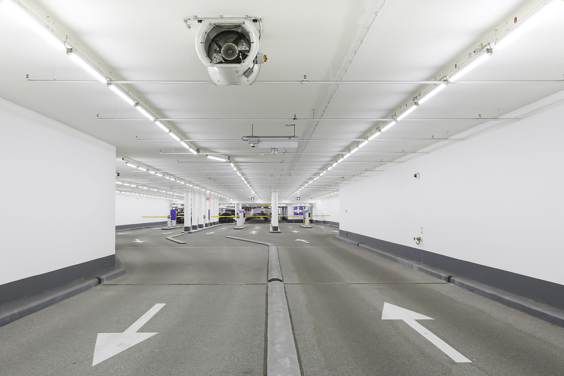 An expansive, vacant car park featuring bright ceiling lights,