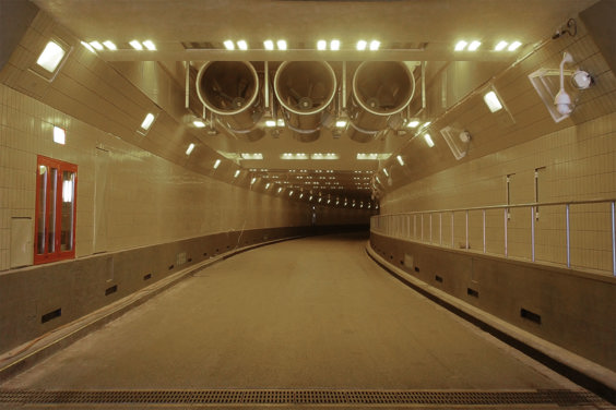 A well-lit tunnel with ventilation in the ceiling, extending into the distance